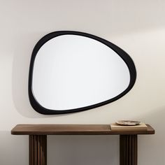 an oval mirror mounted on the wall above a wooden table