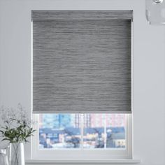 a window with a gray roller shade in front of a white wall and windowsill