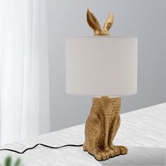 a golden rabbit lamp sitting on top of a bed