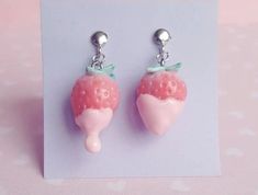 two strawberry shaped earrings with bows on them