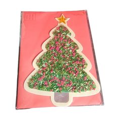 a pink box with a christmas tree on the front and green sprinkles on the back