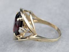 This is a stunning cocktail mounting crafted from shining yellow gold! The ring is really all about the center stone, and the simple styling and accent diamonds create the perfect stage! Deep, crimson red, this garnet is the color of a fine cabernet, poured in a golden glass.Metal: 14K Yellow GoldGem: Garnet 6.50 CaratsGem Measurements: 13.2 x 10.6 mm, OvalAccents: 2 Diamonds totaling .10 Carats, I1 in Clarity, G in ColorRing Size: 6.75Marks: "14KP" Stamped on the inside band Garnet Center Stone Yellow Gold Jewelry, Yellow Gold Garnet Rings With Gemstone Accents, Garnet Cocktail Ring, Polished Yellow Gold Garnet Jewelry, Yellow Gold Garnet Jewelry With Polished Finish, Diamond Cocktail Rings, Cocktail Rings, Garnet, Yellow Gold