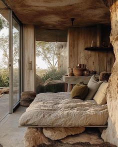 a bed sitting inside of a bedroom next to a stone wall and glass door leading outside