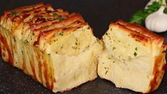 some kind of food that is cut in half on a black surface with garlic and parsley