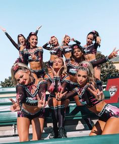 a group of cheerleaders posing for a photo in front of a bench with their hands up