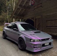 a purple car parked in front of a wooden building