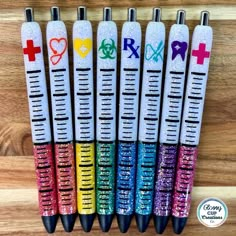 six pens with different designs on them sitting in front of a wooden table and the words love