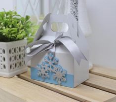 a small white box with a snowflake decoration on the side and a potted plant next to it