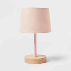 a pink lamp with a wooden base on a white background