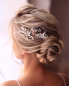 a woman wearing a bridal hair comb with flowers on it's head, looking off to the side