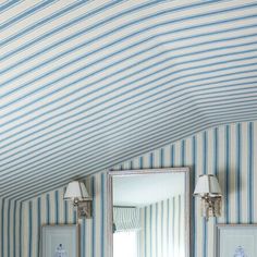 a bathroom with blue and white stripes on the walls, two sinks and a mirror