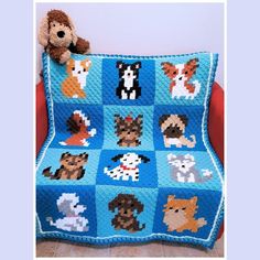 a crocheted blanket with dogs on it and a teddy bear sitting next to it