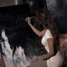 a woman is sitting on the floor painting