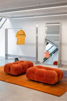 two orange bean bags sitting on top of an orange rug in front of a mirror