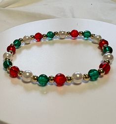 a bracelet with red, white and green beads on a white tableclothed surface