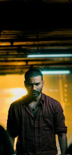 a man with a beard standing in front of a yellow wall and looking at the camera