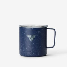 a blue mug with a white bird on the side and stars in the sky behind it