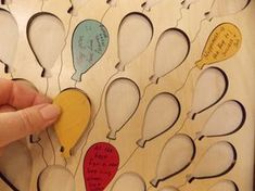 a person holding a piece of wood with many balloons on it and writing on the side