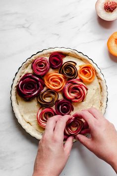 someone decorating a fruit tart on a table with the title stone fruit and frangane summer fruit tart