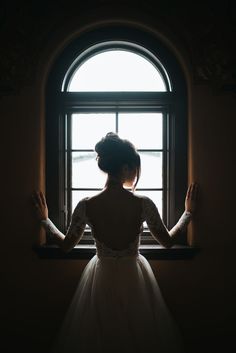 a woman standing in front of a window with her hands on the window sill