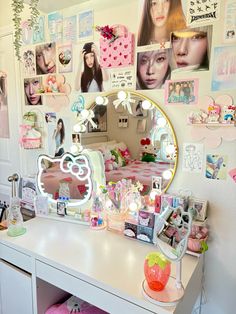 a white desk topped with a vanity mirror and lots of pictures on the wall behind it