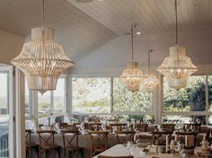 a dining room filled with lots of tables and chairs under chandelier hanging from the ceiling