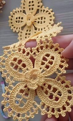 two pieces of crochet are being held by someone's hand