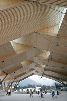 people are walking around in the snow under a wooden structure that is suspended from the ceiling