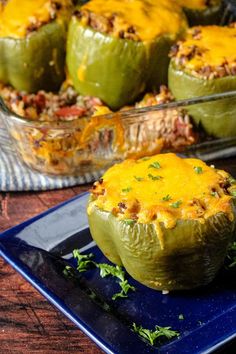 stuffed peppers with meat and cheese on a blue plate next to a casserole dish