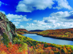 a scenic view of a lake surrounded by trees and mountains in the fall with colorful foliage