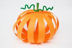 an orange paper pumpkin with green ribbon on it