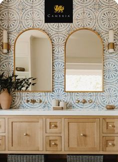 a bathroom with blue and white tiles on the wall, two mirrors above the sink