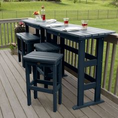 an outdoor bar with three stools on a deck in front of a grassy field