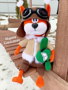 a crocheted stuffed animal is sitting on a bench in the snow with goggles