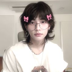 a girl with glasses and pink bows on her head is looking at the camera while wearing a white shirt