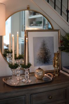 a christmas scene with candles, ornaments and pictures on a table in front of a staircase