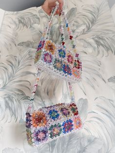 a hand holding two bags made out of beads