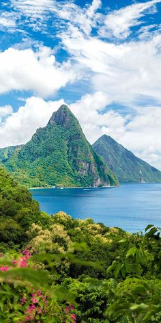 an island surrounded by lush green trees and blue water with mountains in the background on a sunny day