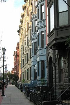 a row of multi - colored buildings on the side of a street in an urban area