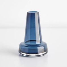 a blue glass vase sitting on top of a white table next to a black object