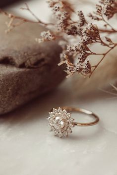 a close up of a ring on a table with flowers and rocks in the background