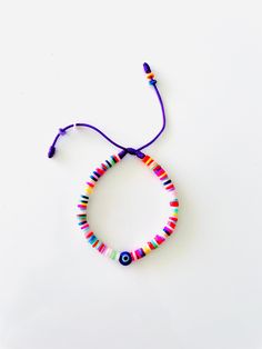 "Heishi Beads Bracelet Strung on a Vibrant Purple String and Accented with the Iconic Blue Evil Eye that has become our brand DNA. Bracelet arrives in a beautiful package with a sweet, meaningful blessing for you and loved ones that reads, \"𝙈𝙖𝙮 𝙮𝙤𝙪 𝙗𝙚 𝙋𝙧𝙤𝙩𝙚𝙘𝙩𝙚𝙙, 𝙃𝙖𝙥𝙥𝙮, 𝙃𝙚𝙖𝙡𝙩𝙝𝙮 𝙖𝙣𝙙 𝙒𝙚𝙖𝙡𝙩𝙝𝙮\". 𝗛𝗲𝗶𝘀𝗵𝗶 𝗣𝗮𝗿𝘁𝘆 https://etsy.me/3p7X8DG 𝗠𝗼𝗿𝗲 𝗘𝘁𝘀𝘆 𝗮𝘄𝗲𝘀𝗼𝗺𝗲𝗻𝗲𝘀𝘀 https://etsy.me/3jMTB8z * Convenient adjustable sliding knot for an easy comfo Purple Bracelet With Sliding Knot For Beach, Purple Sliding Knot Bracelet For The Beach, Handmade Purple Stretch Bracelet For Beach, Beach Jewelry With Sliding Knot In Purple, Beach Jewelry With Purple Sliding Knot, Purple Jewelry With Sliding Knot For Beach, Purple Beaded Friendship Bracelet With Sliding Knot, Multicolor Evil Eye Beaded Bracelets For Friendship, Casual Multicolor Evil Eye Bracelet For Beach