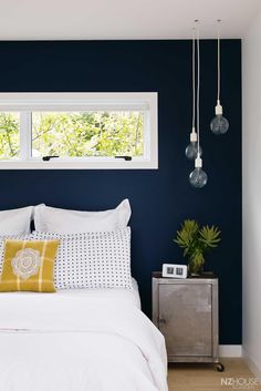 a bedroom with blue walls, white bedding and yellow pillows on the headboard