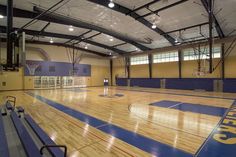 an indoor basketball court with blue and yellow painted flooring is seen in this image