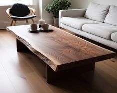 a wooden table with two cups on it in front of a white couch and chair