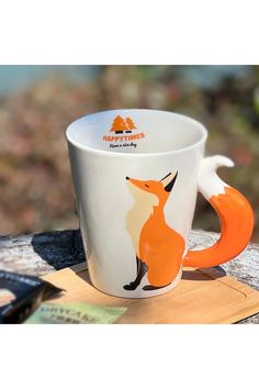 a coffee cup with an orange fox design on the inside sits on a piece of wood