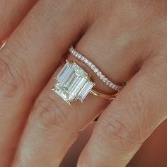 a woman's hand with a diamond ring on top of her finger and an engagement band