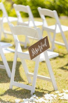 white chairs with wooden signs on them sitting in the grass