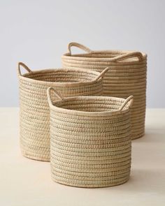 three large woven baskets sitting on top of a table next to each other with handles