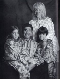 an old black and white photo of a family posing for the camera with one child on his lap